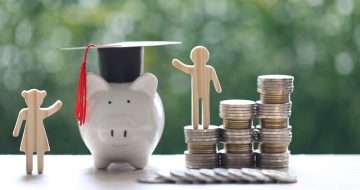 Graduation hat on piggy bank with stack of coins money on natural green background, Saving money for education concept