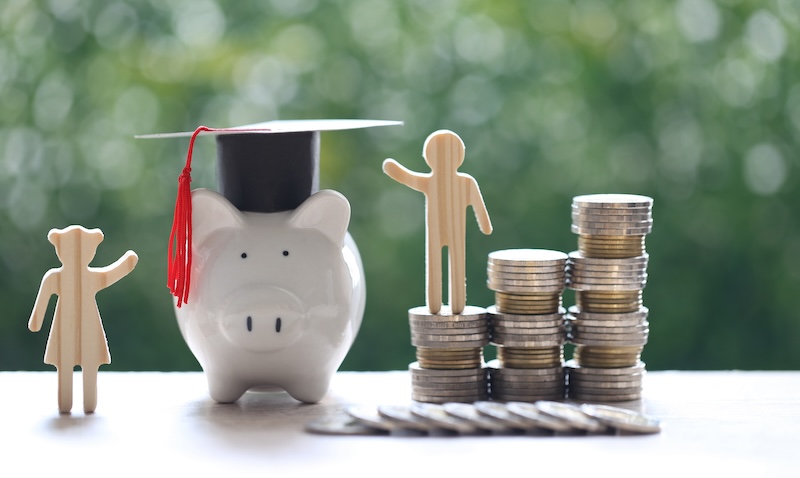 Graduation hat on piggy bank with stack of coins money on natural green background, Saving money for education concept