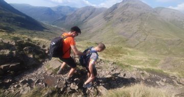 Michael holds onto Jack's backpack to be guided down the mountain