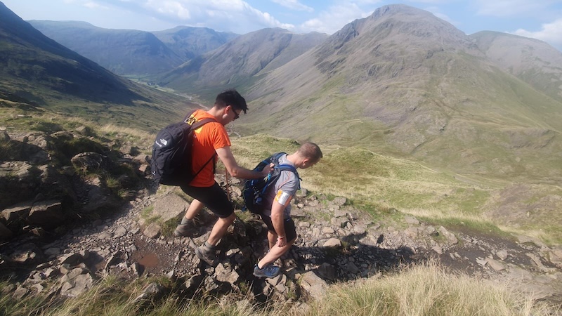 Michael holds onto Jack's backpack to be guided down the mountain